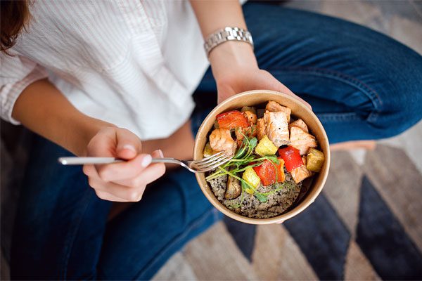 Photo of a woman eating a bowl of healthy food