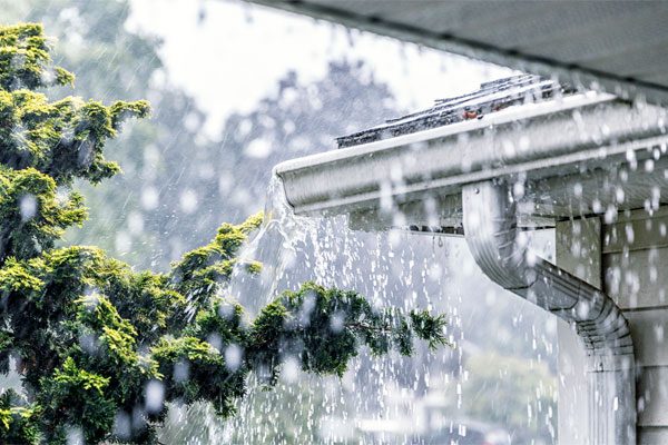 Photo of rain pouring off a house roof