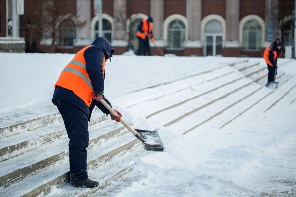 Photo of 3 workers clearing snow from the steps