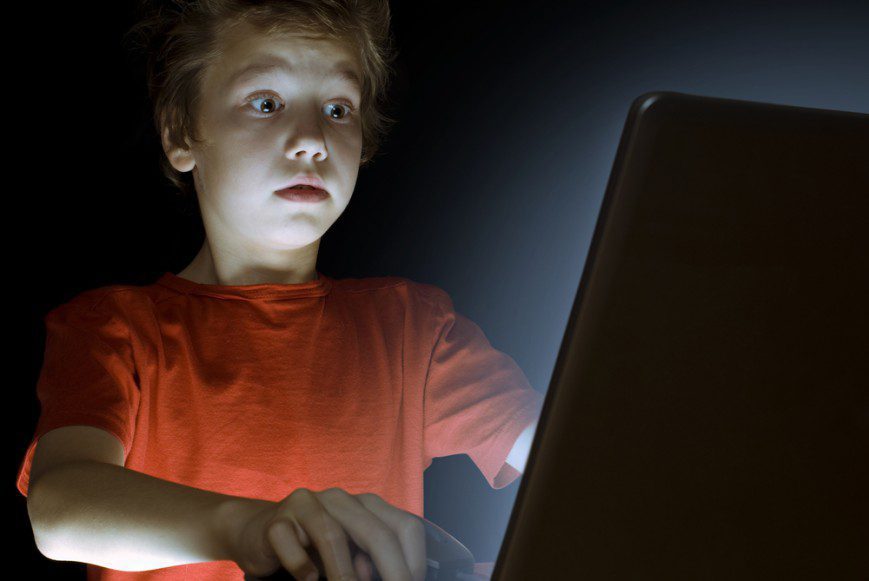 Young boy surprised looking at computer screen