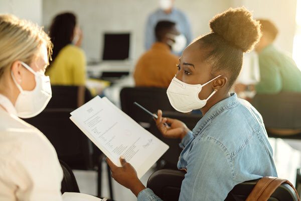 Woman in a mask chatting with another woman used for "Four Key Insights for Effective Risk Management of Sexual Abuse and Molestation Incidents" blog post