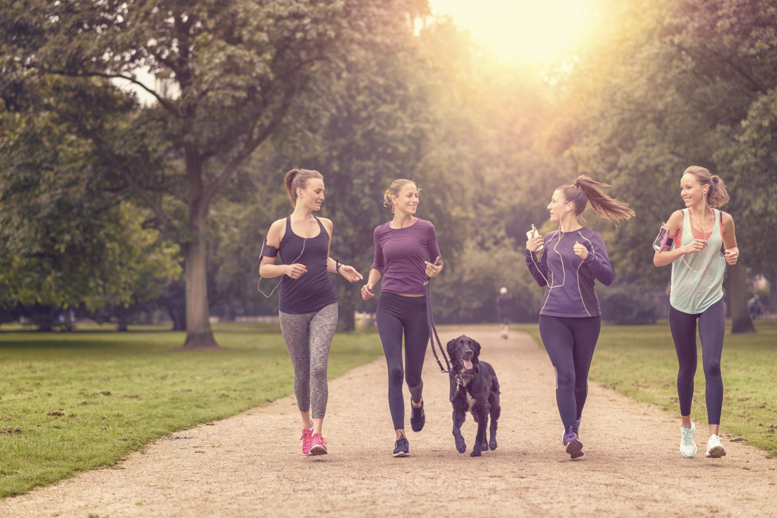 Group of women running with a dog, smiling