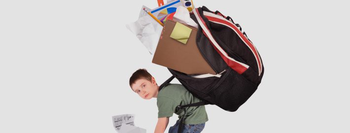 Young boy frowning slouched over with a big heavy backpack on