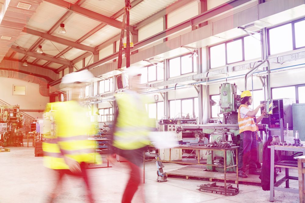 Manufacturing plant, two men in construction uniforms walking by quickly