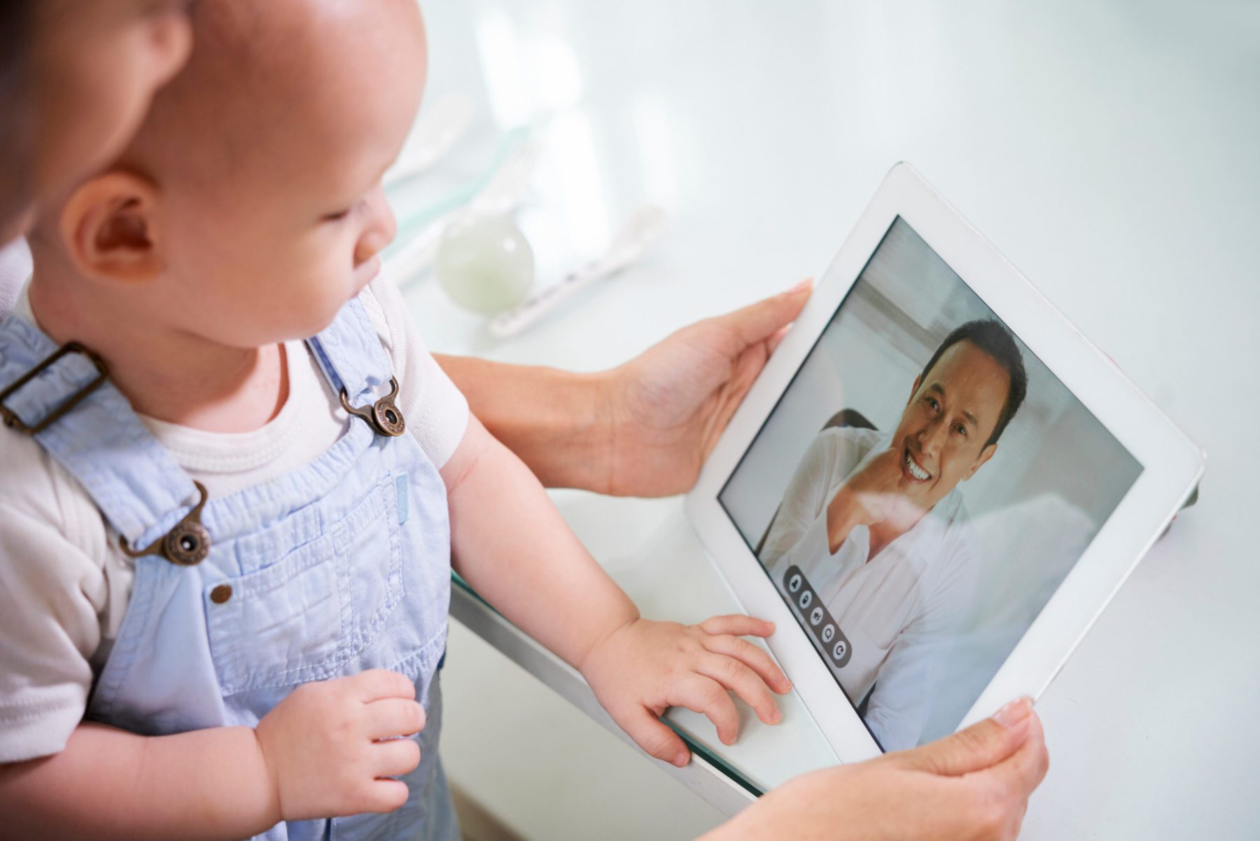 Baby and parent looking at technology screen with a man