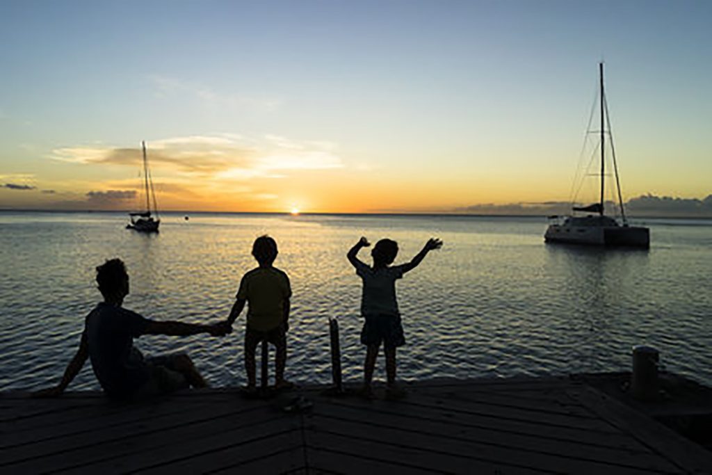 Children and parent watching the sunrise on a dock