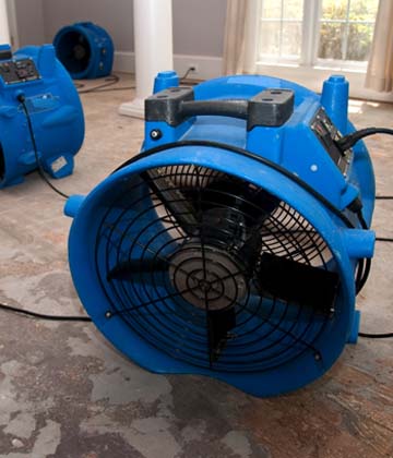 A couple industrial fans in a room to help the drying and restoration process of the sewage water damage