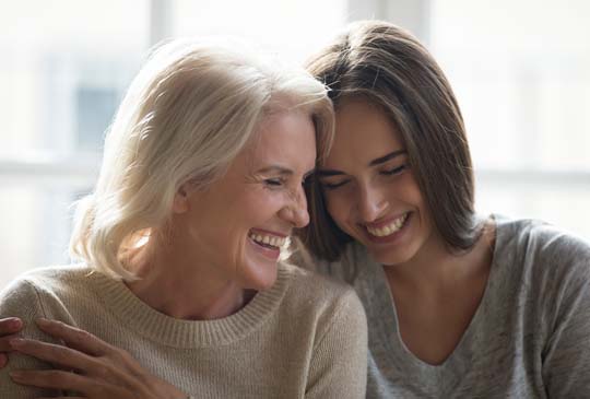 Two women laughing with their heads close together