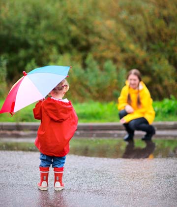A child holding an umbrella facing their parent in the distance