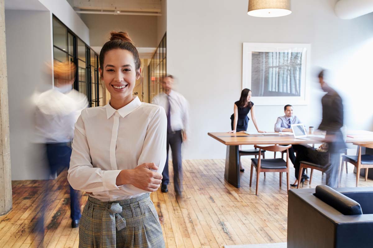 A women posing and smiling with her arms crossed while in a work environment