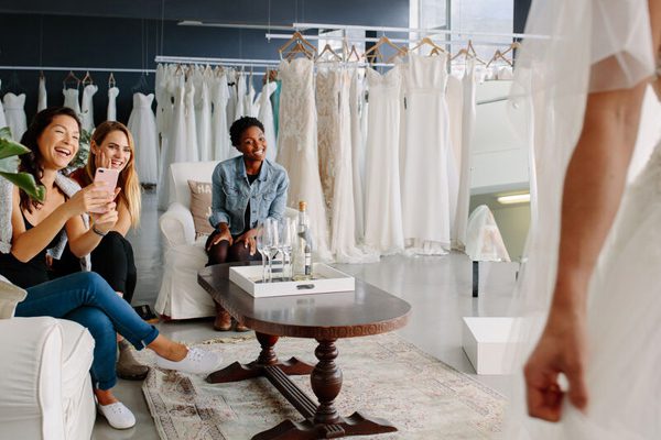 Women dressed in wedding gown with friends at a bridal boutique