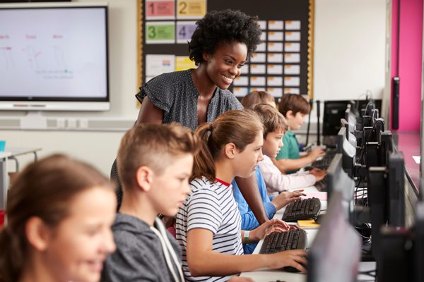 A photo of a teacher and students working on computers at an independent school