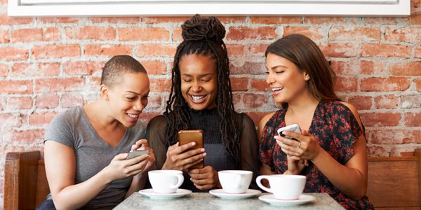 Photo for the Fred C. Church referral program, with several friends looking at their smartphones and sharing information.